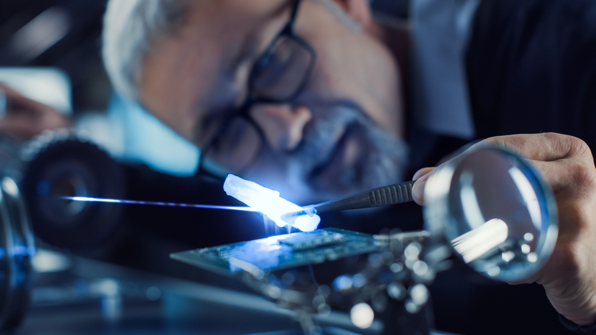 Close-up Portrait of Focused Middle Aged Engineer in Glasses Working with High Precision Laser Equipment, Using Lenses and Optics for Accuracy