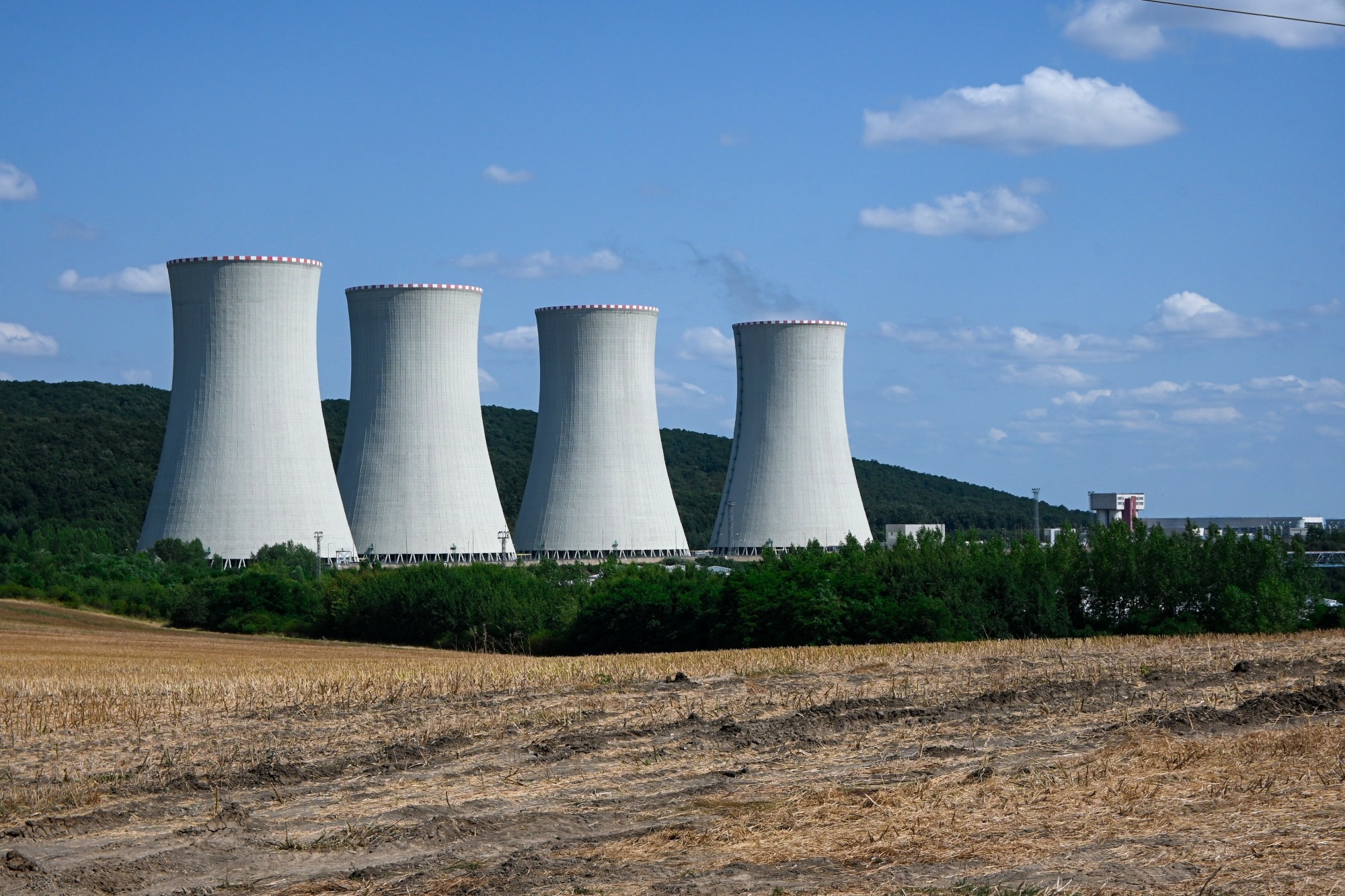 Four large nuclear power plant cooling towers releasing steam into the atmosphere.