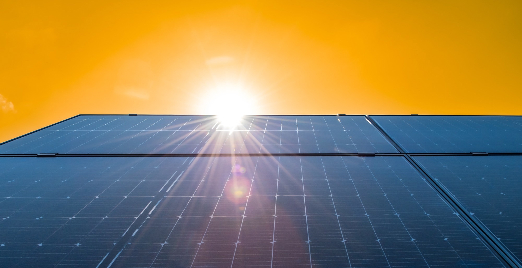 Photovoltaic solar panels against bright yellow sky background. Energy-saving and innovation concept.