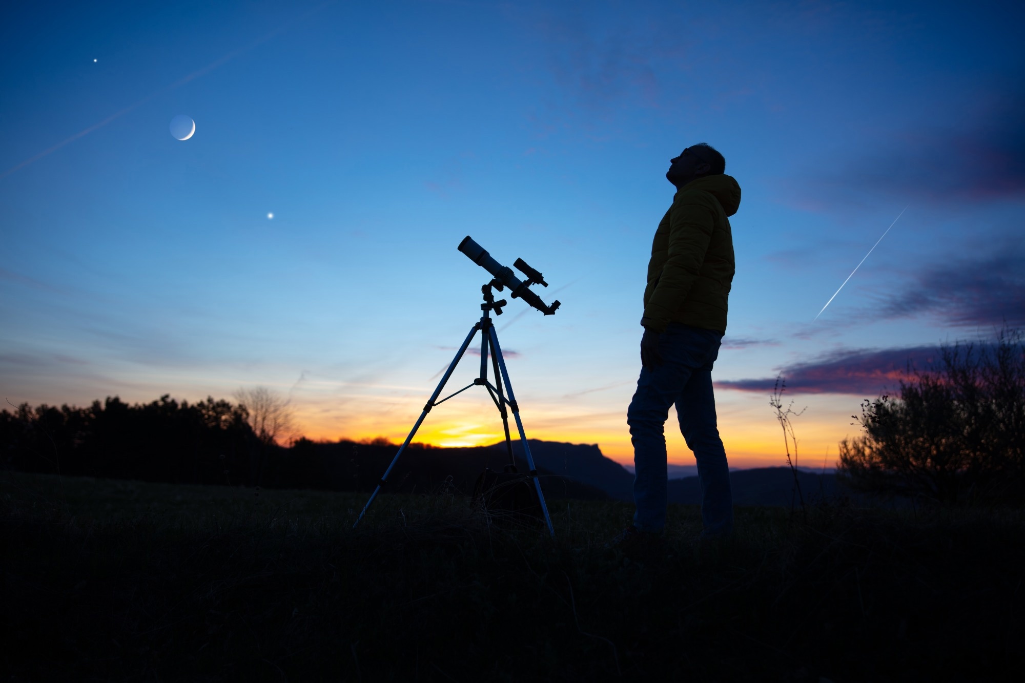 Amateur astronomer looking at the evening skies, observing planets, stars, Moon and other celestial objects with a telescope