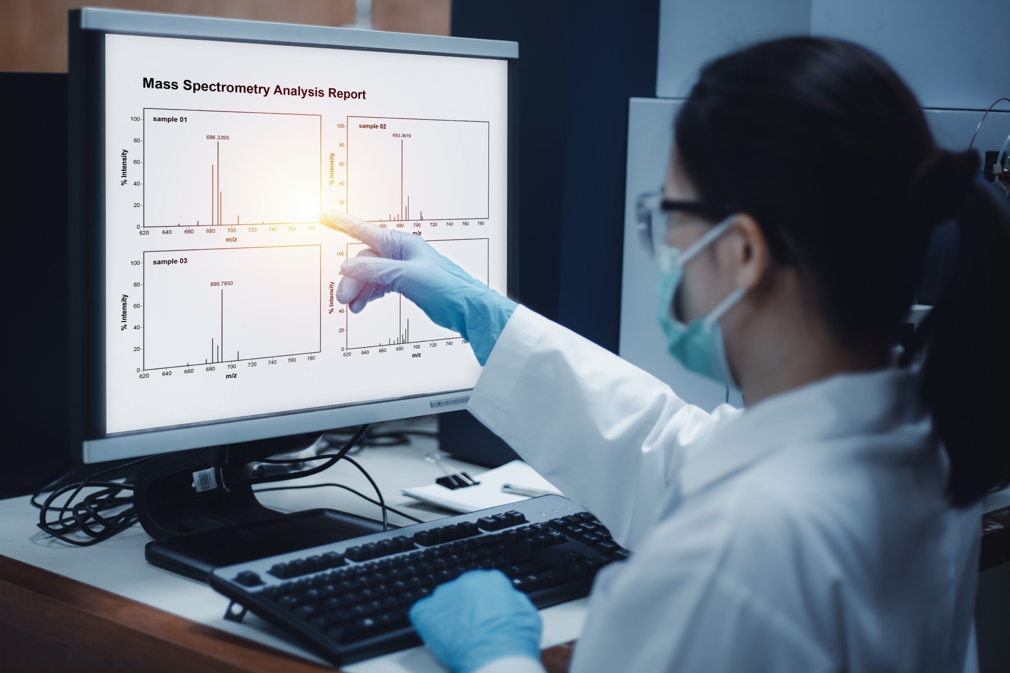 Scientist woman indicates the chromatogram of mass spectrometry analysis results of compounds, as shown on the computer monitor of mass spectrometer instrument in the laboratory.