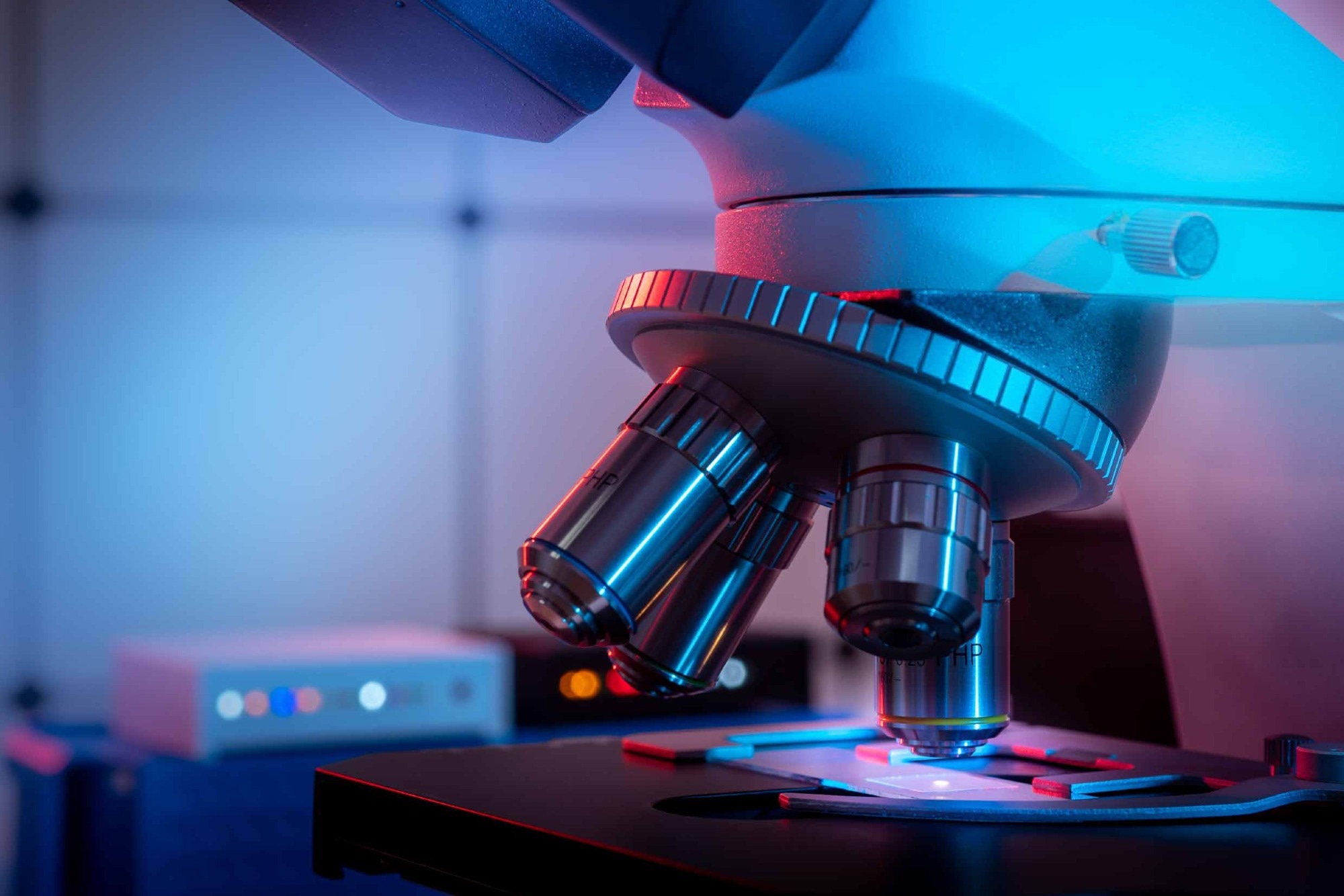 Toned photo of a backlit microscope lens in a science laboratory.