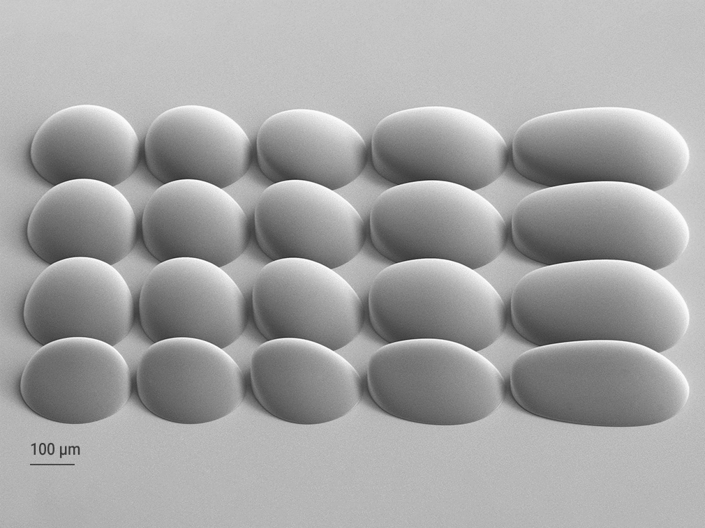 Array of freeform microlenses fabricated with Quantum X litho using Two-Photon Grayscale Lithography, shown as 2.5D-printed master and corresponding nickel shim for replication. A) SEM image of the 2.5D master template for a freeform microlens array and B) the mold tool generated from the master by electroforming, the mold tool is then used for replication via micro injection molding, enabling large scale series production for industrial microfabrication