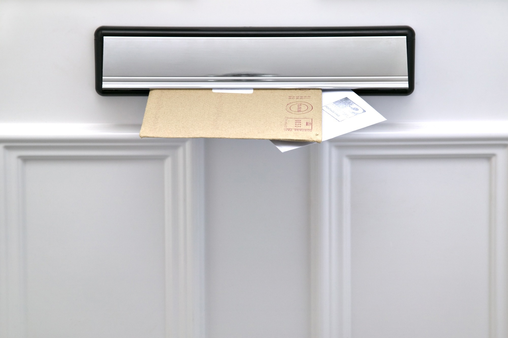Two letters sticking out of a letterbox on a white door