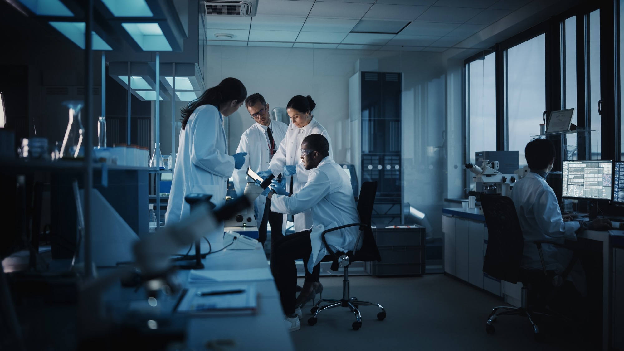 Scientists in a lab stand around an mobile device.