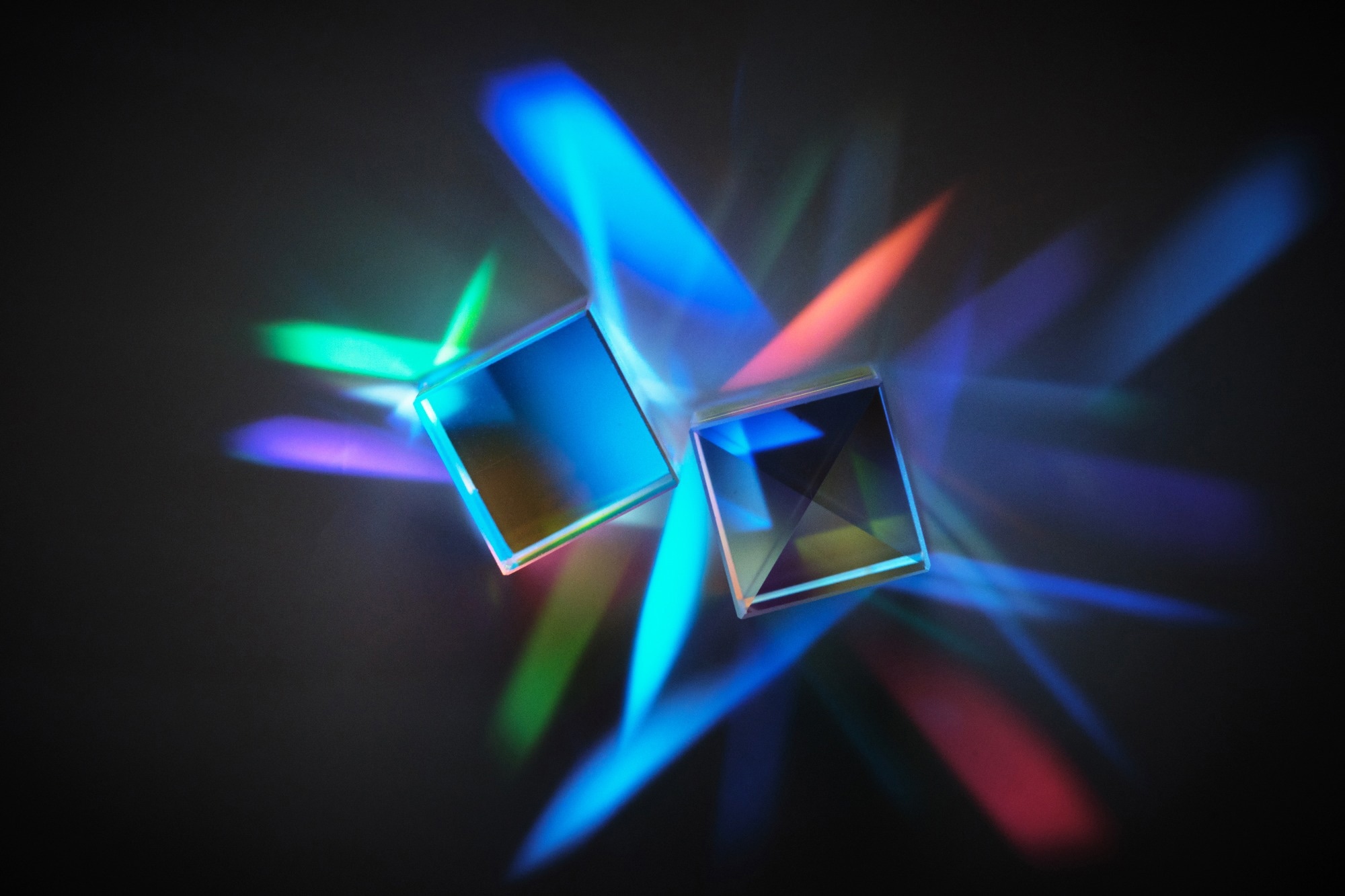 A clear prism with colourful light reflecting and bouncing off it.